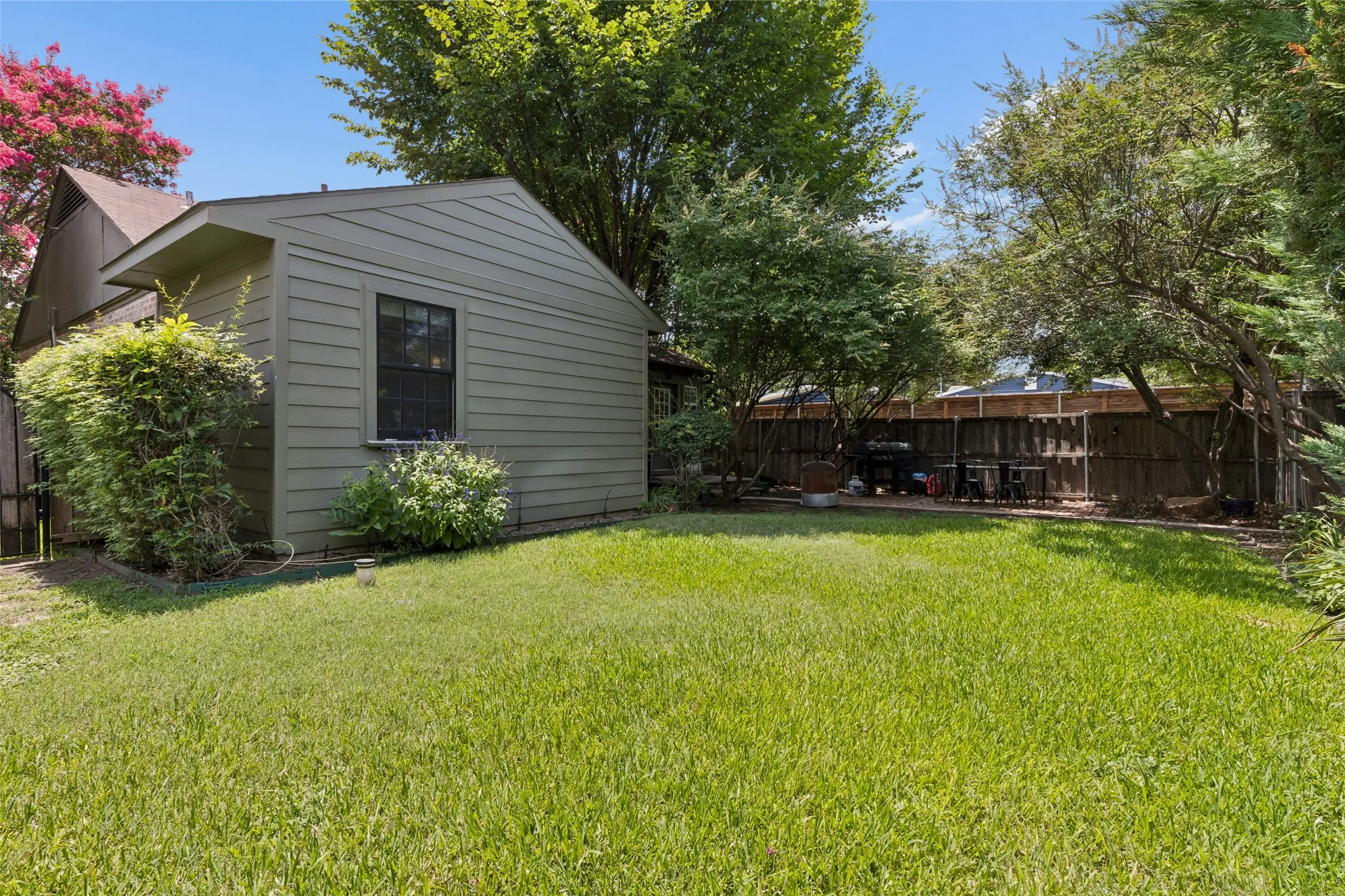 Expansive grassy yard with a privacy fence and mature trees