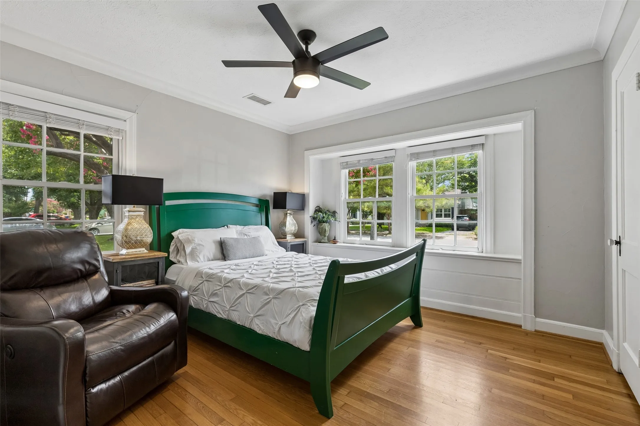 Wood-finish flooring, multiple pane windows, crown molding, and a ceiling fan with integrated lighting