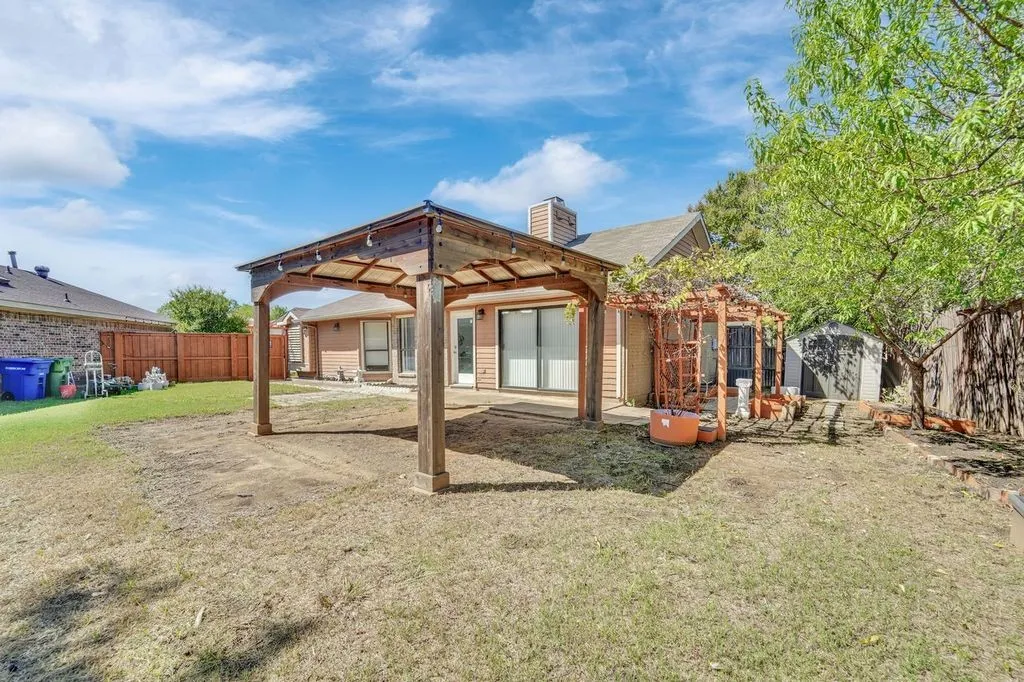 Outdoor space featuring a covered patio, a separate wooden pergola, and a storage shed