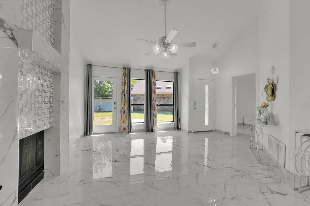 High-gloss tile flooring, vaulted ceiling, decorative fireplace with tile surround, ceiling fan, and transom windows