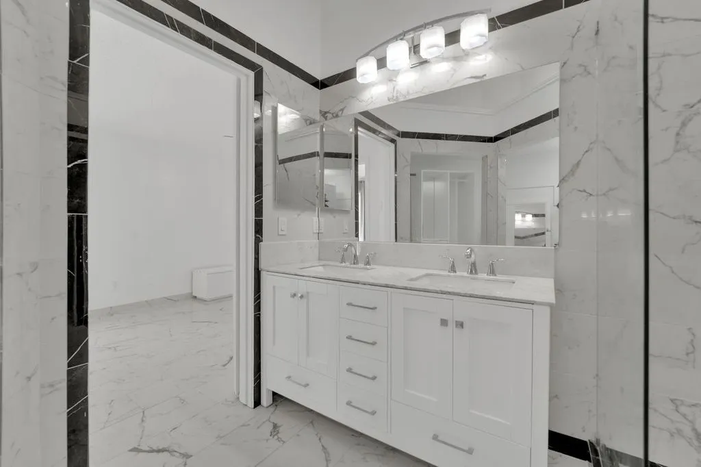 Dual vanity with undermount sinks, chrome fixtures, and white cabinetry