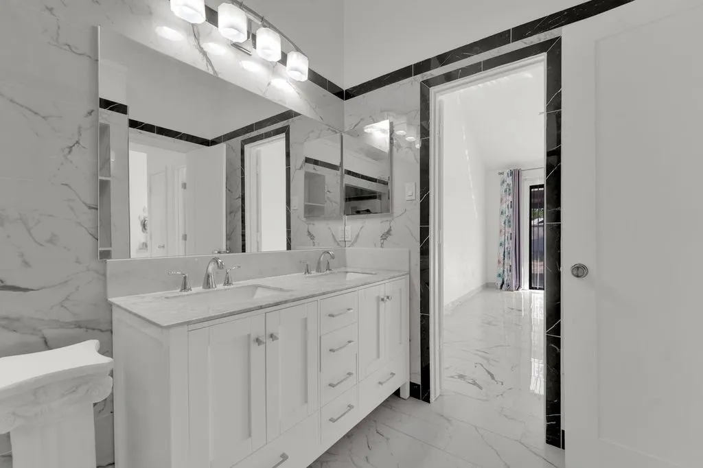 Dual vanity with undermount sinks and chrome fixtures, illuminated by a four-light fixture