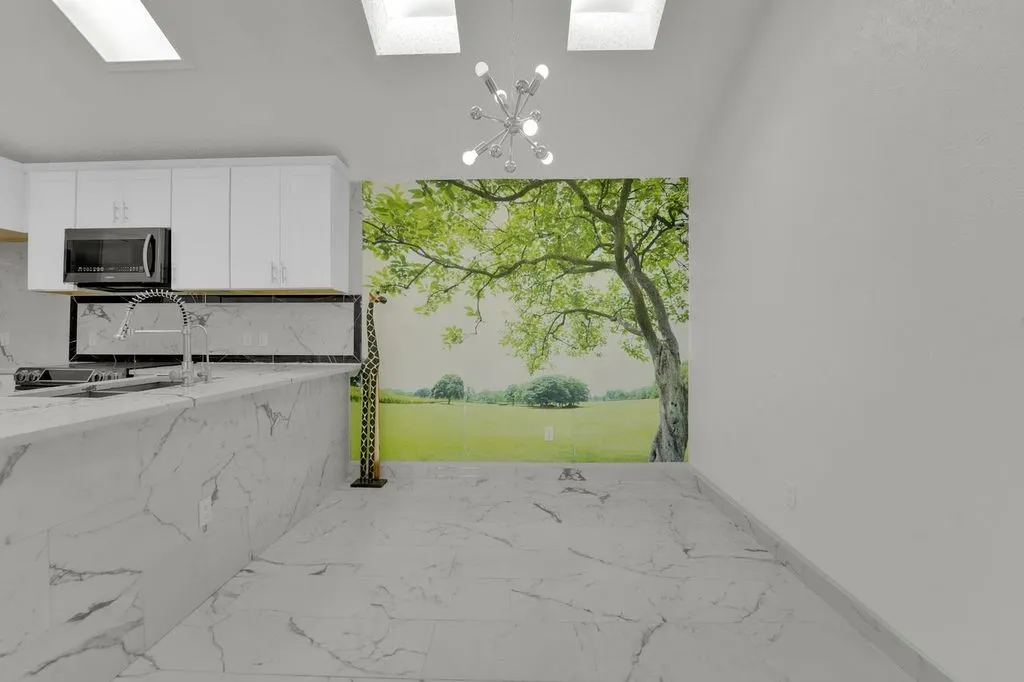 White cabinetry with dark hardware, stainless steel microwave, and a chrome pull-down faucet
