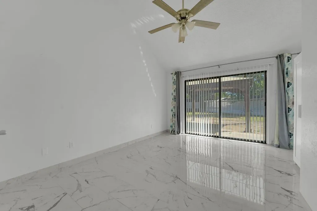 High ceilings with a ceiling fan, sliding glass door with vertical blinds, and polished tile flooring