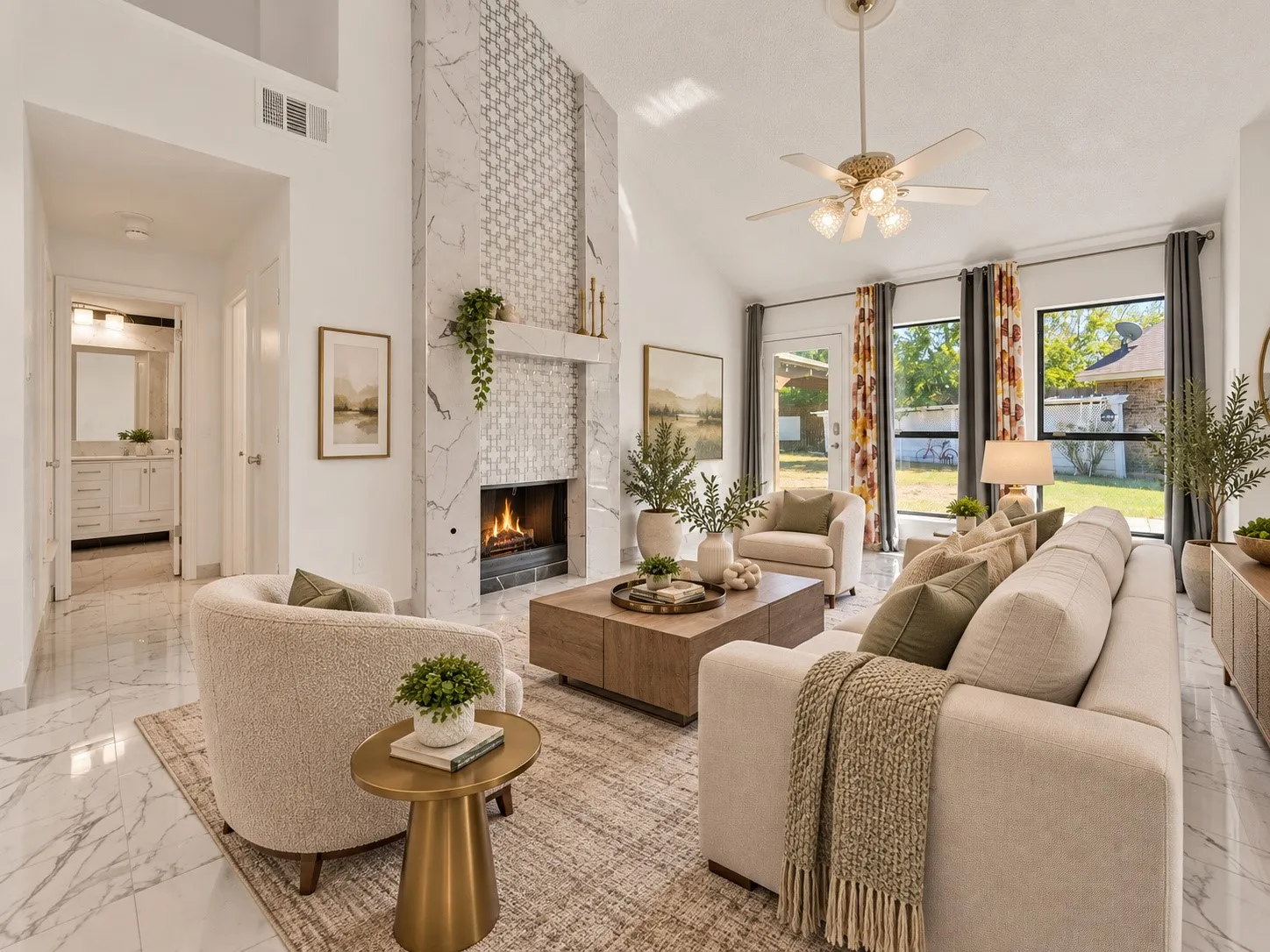 Vaulted ceiling with an attached ceiling fan, large windows with black framing, fireplace with a tile surround and mantel, and glossy tile flooring