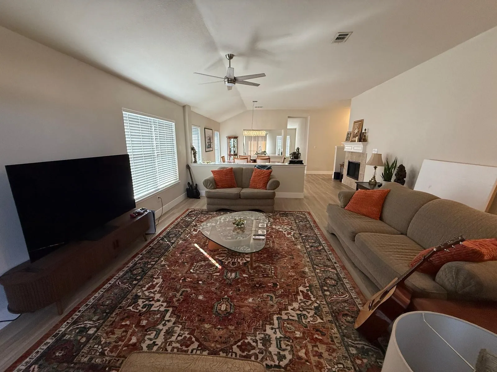 Vaulted ceiling, ceiling fan, wood-finish flooring, fireplace with mantel, window with blinds