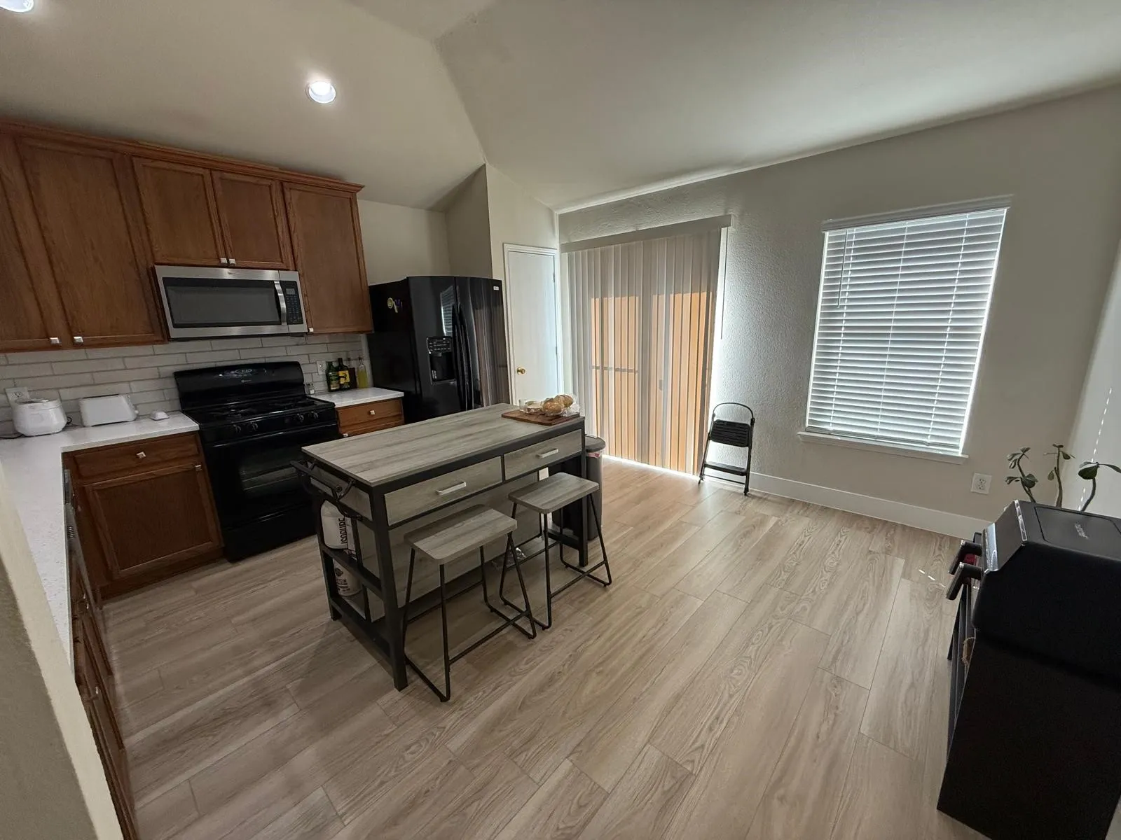 Kitchen featuring wood-finish cabinetry, white countertops, a subway tile backsplash, and stainless steel appliances