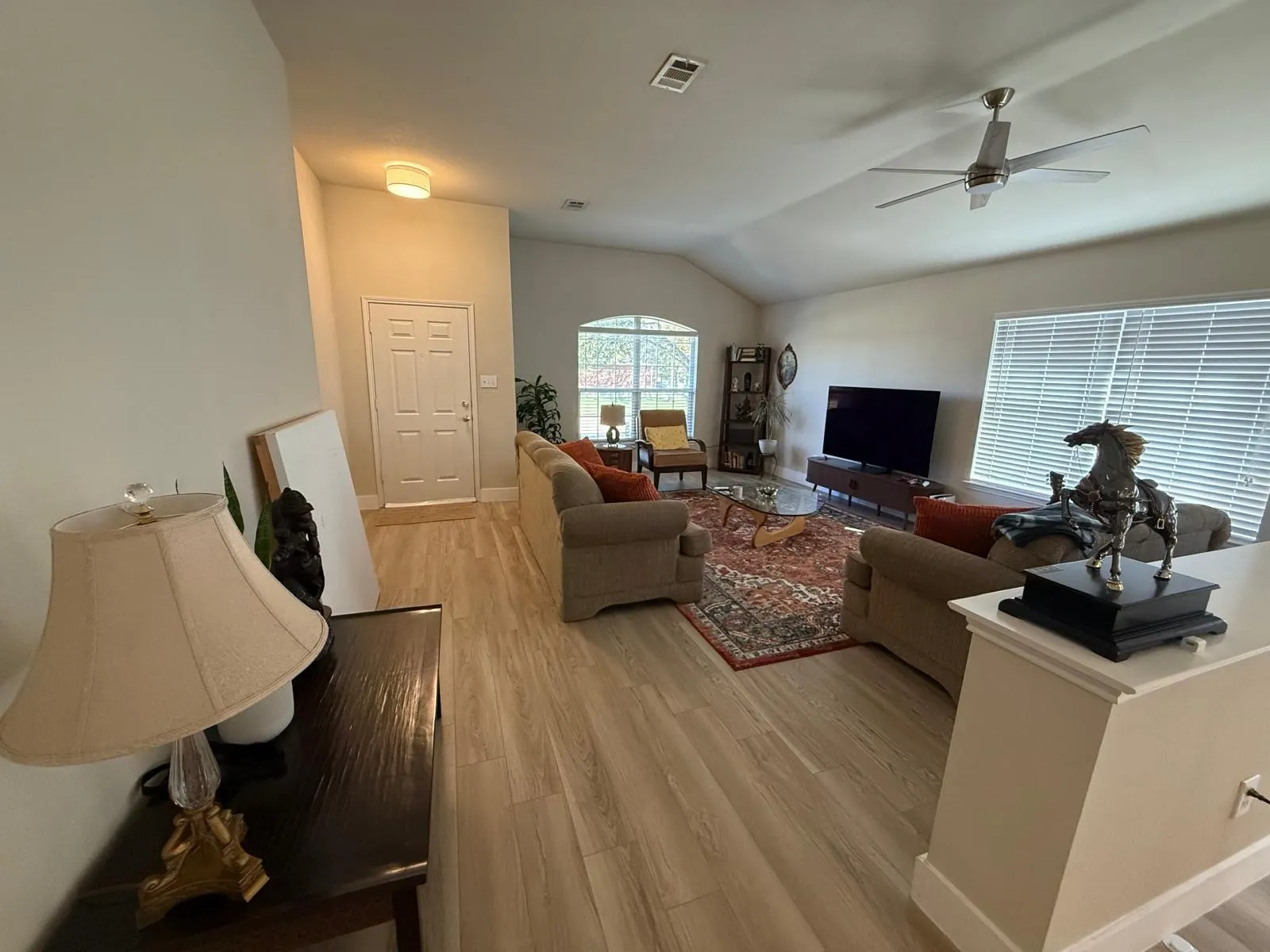 Vaulted ceiling with a ceiling fan, wood-finish flooring, arched window, and window blinds