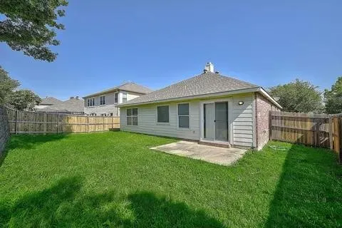 Expansive backyard featuring a manicured lawn, mature shade trees, and wooden privacy fencing