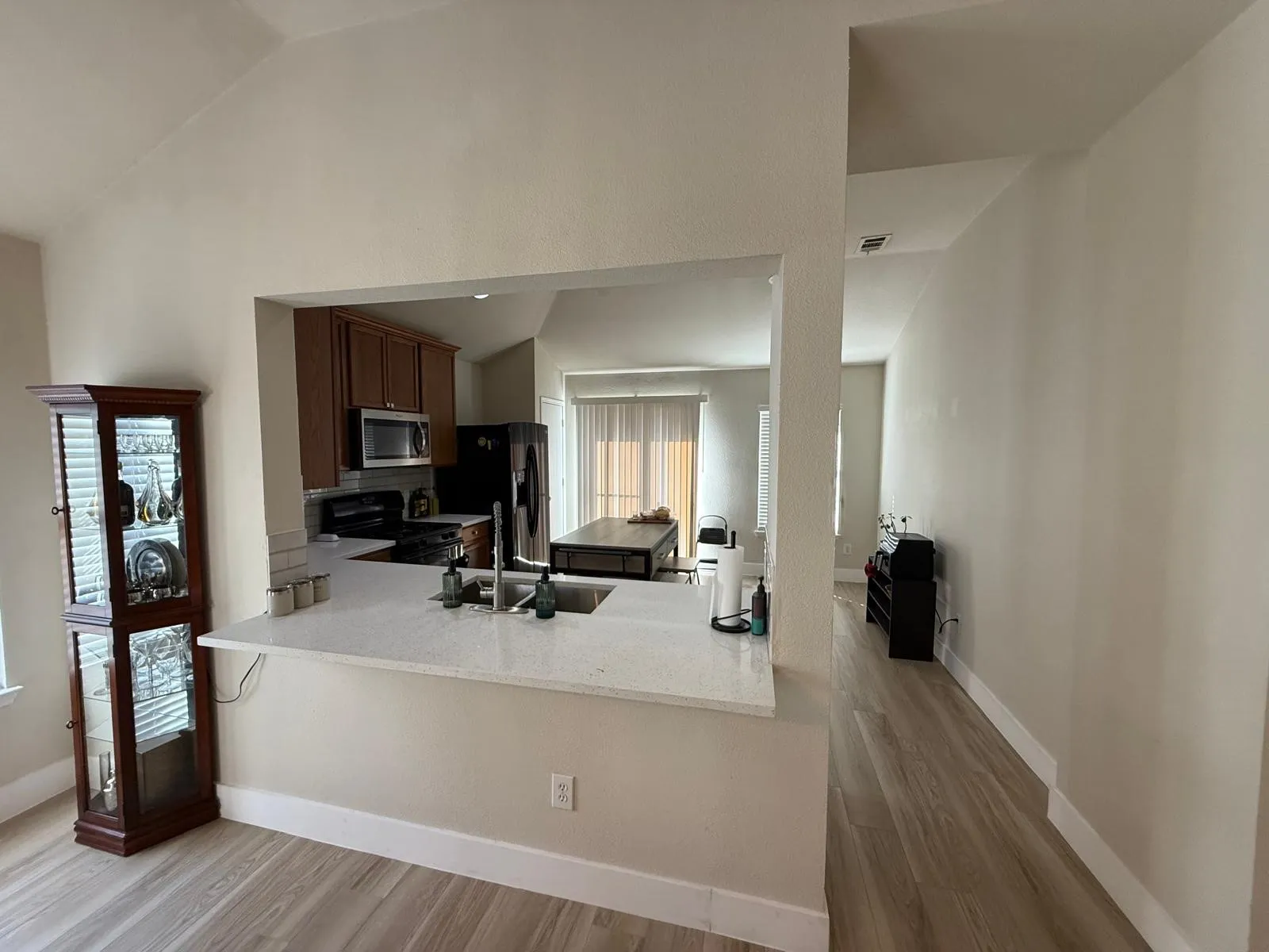 Kitchen with wood cabinetry, stainless steel appliances, white countertop, and subway tile backsplash
