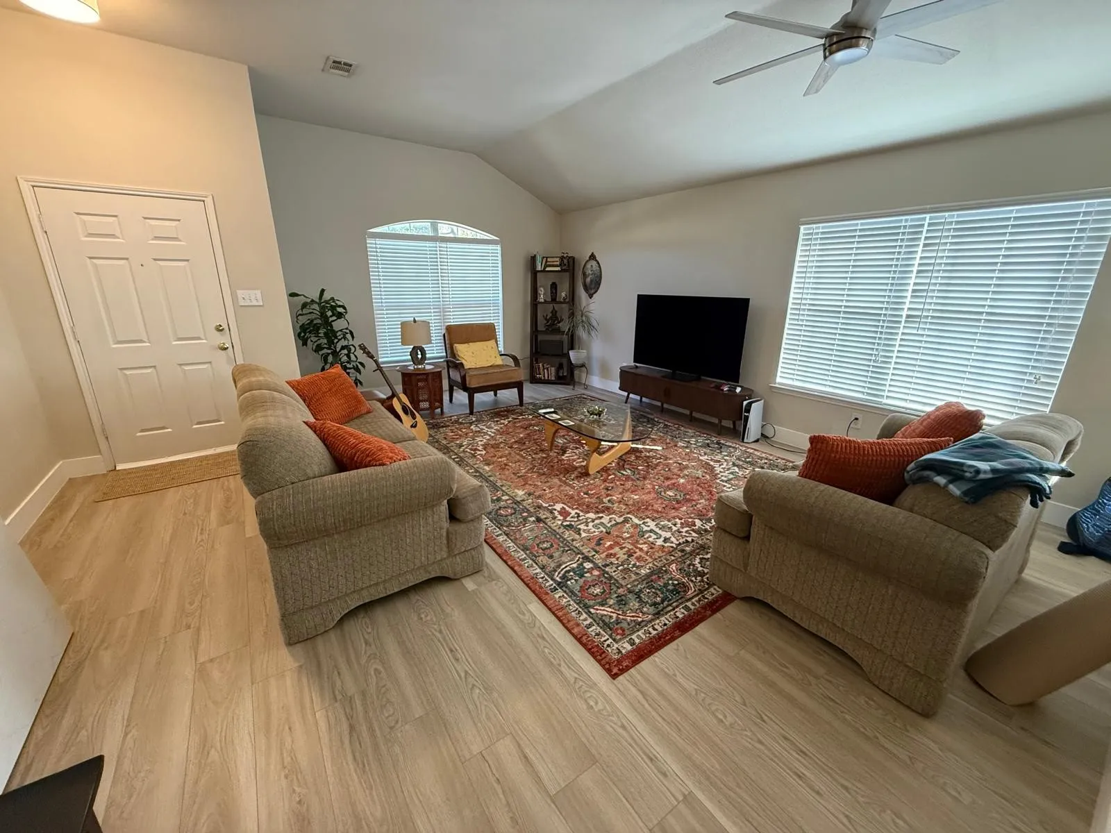 Vaulted ceiling with a ceiling fan, recessed arched window, wood-finish flooring, and white window blinds