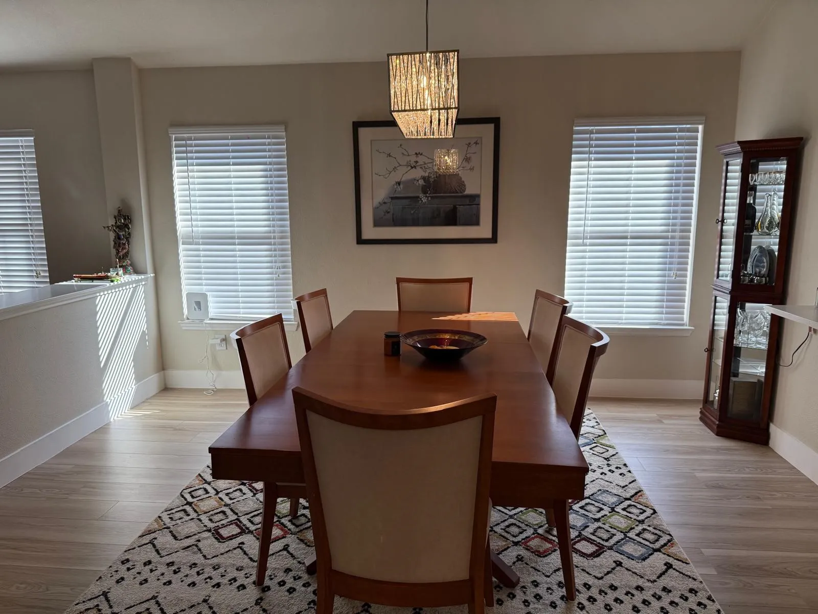 Recessed wall detail, three windows with blinds, wood-finish flooring, and a contemporary chandelier