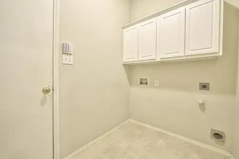 White cabinetry with crown molding, wall-mounted electrical outlets, and a utility hookup