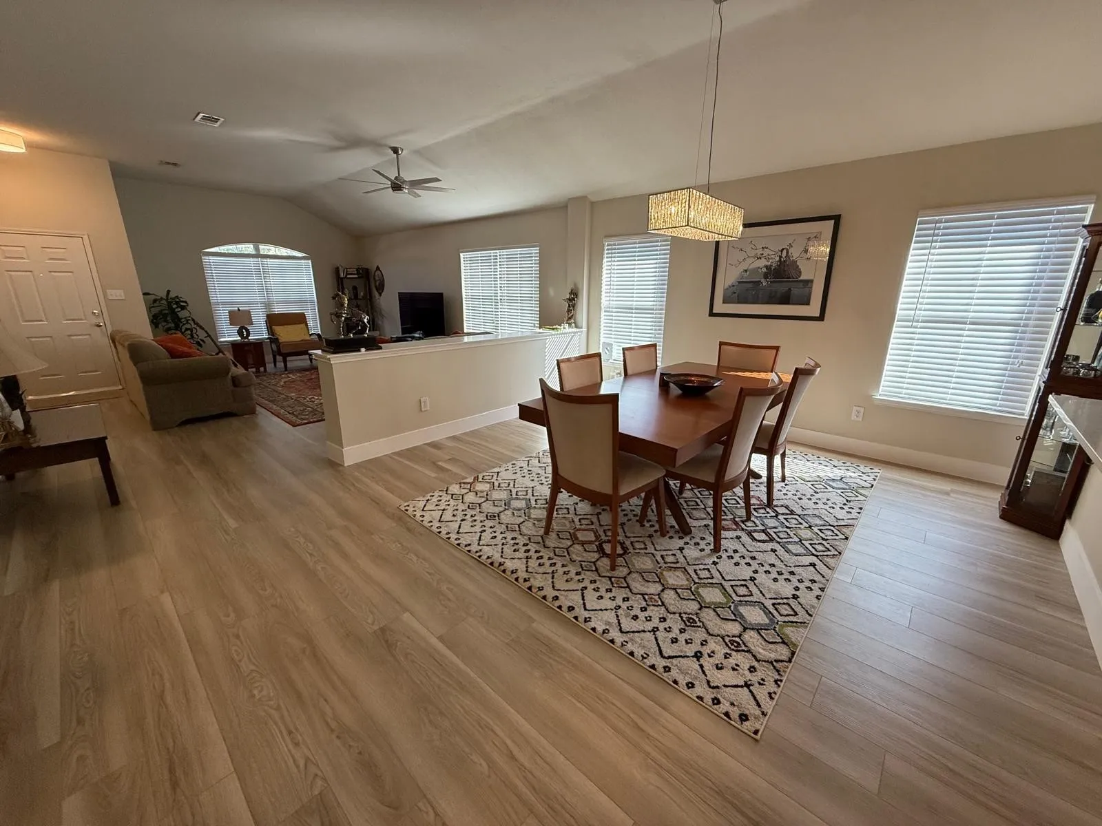 Vaulted ceilings, wood-finish flooring, half-wall divider, rectangular chandelier, and arched window