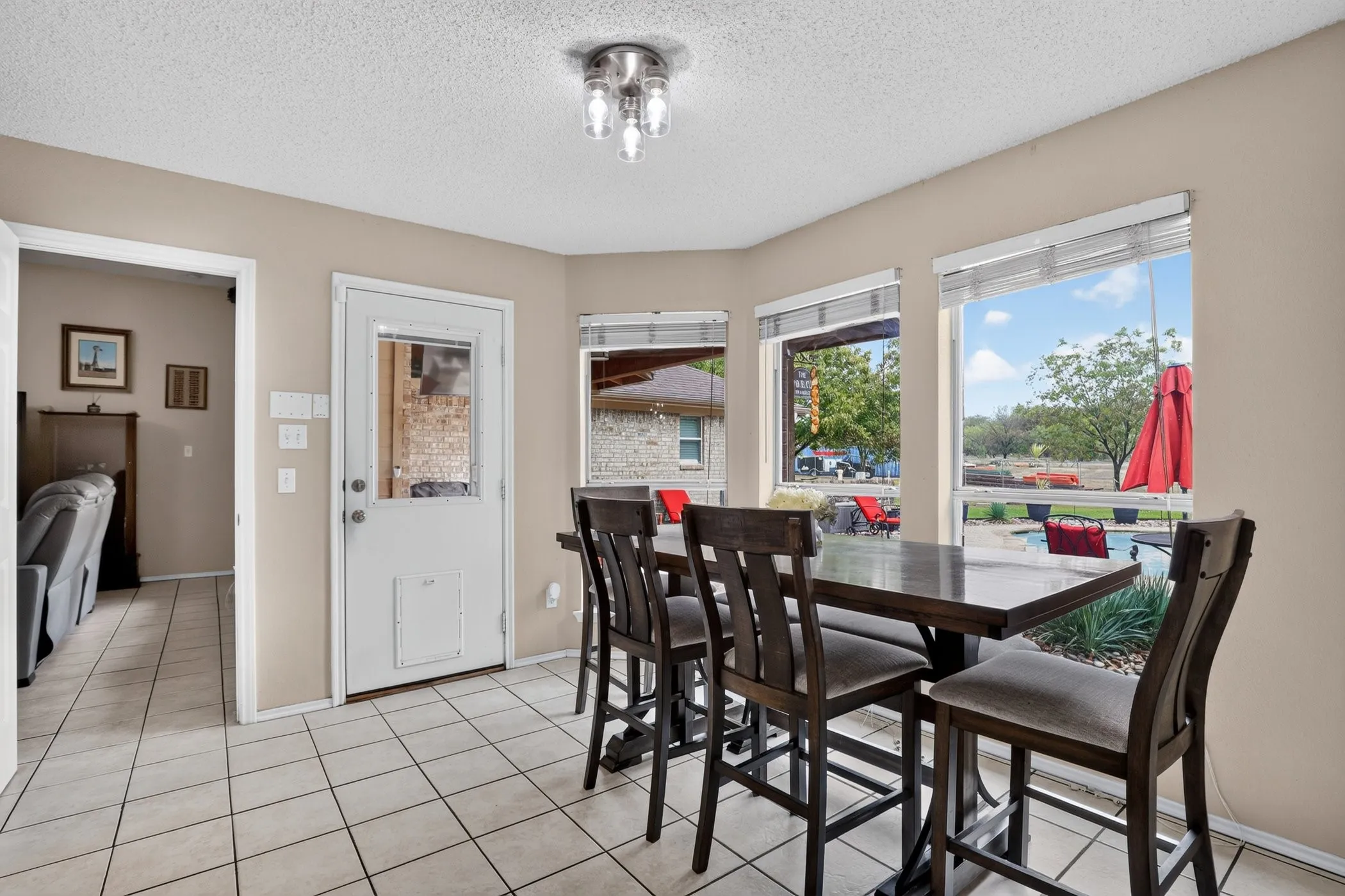Bay window with multiple large windows, recessed ceiling light fixture, white tile flooring, and direct outdoor access