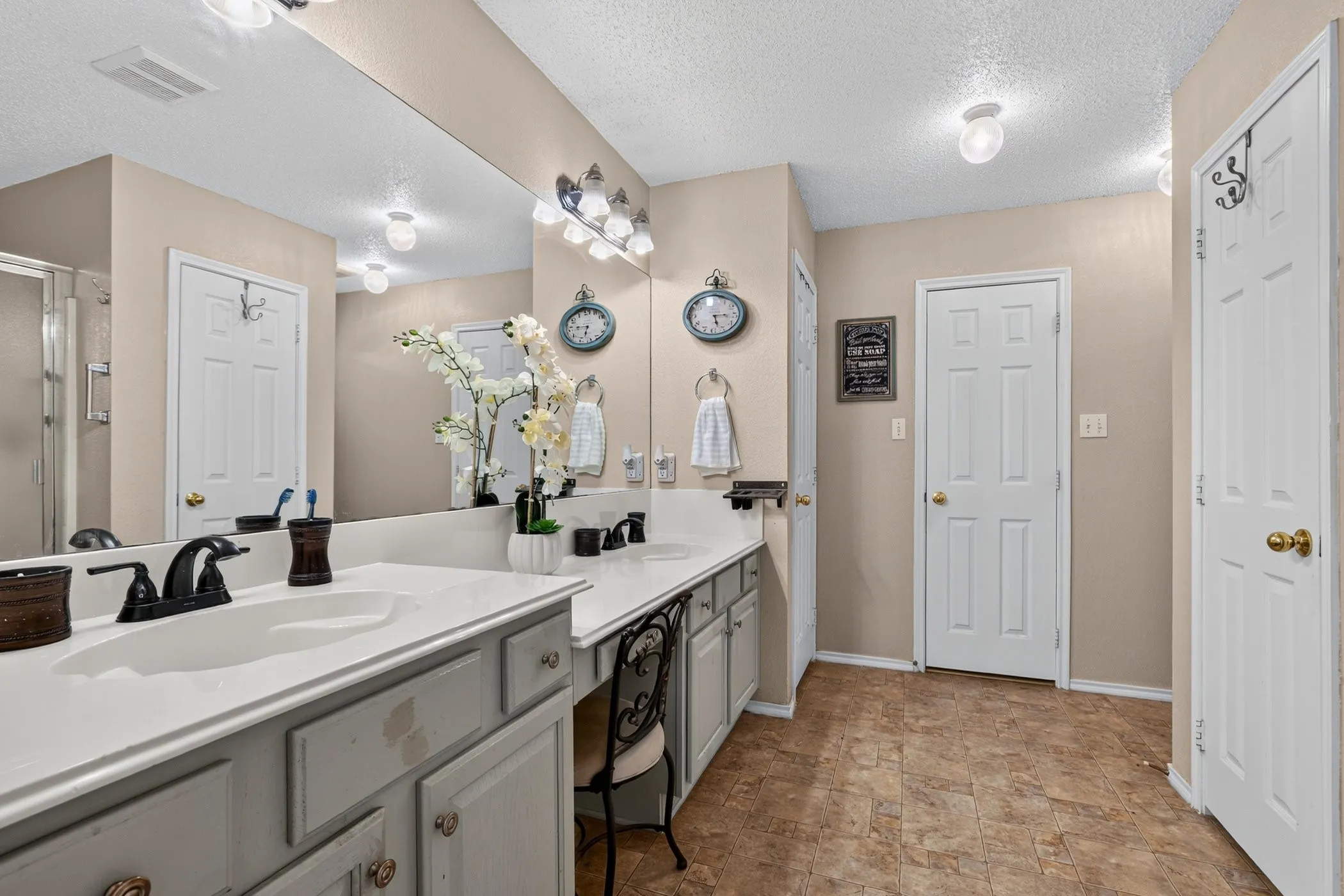 Dual vanity with integrated sinks, expansive wall mirror, and dedicated vanity seating area