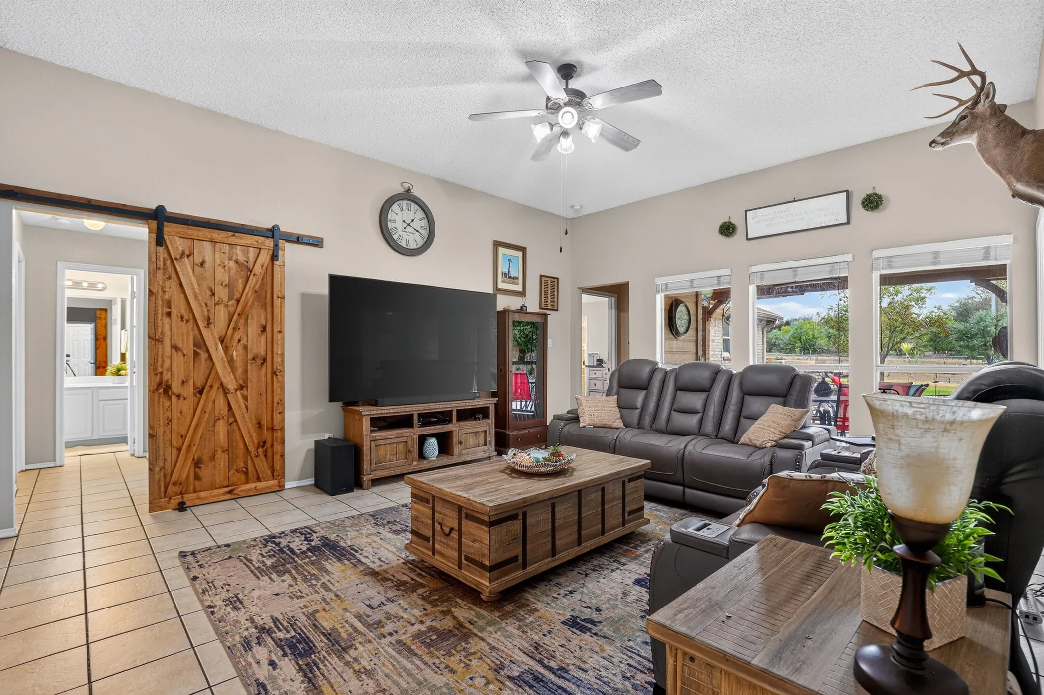 Spacious living area featuring high ceilings, tile flooring, and multiple windows