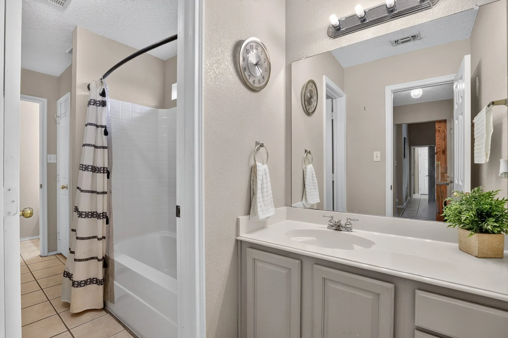 Bathroom featuring a vanity with an integrated sink, broad wall-mounted mirror, and a three-light fixture