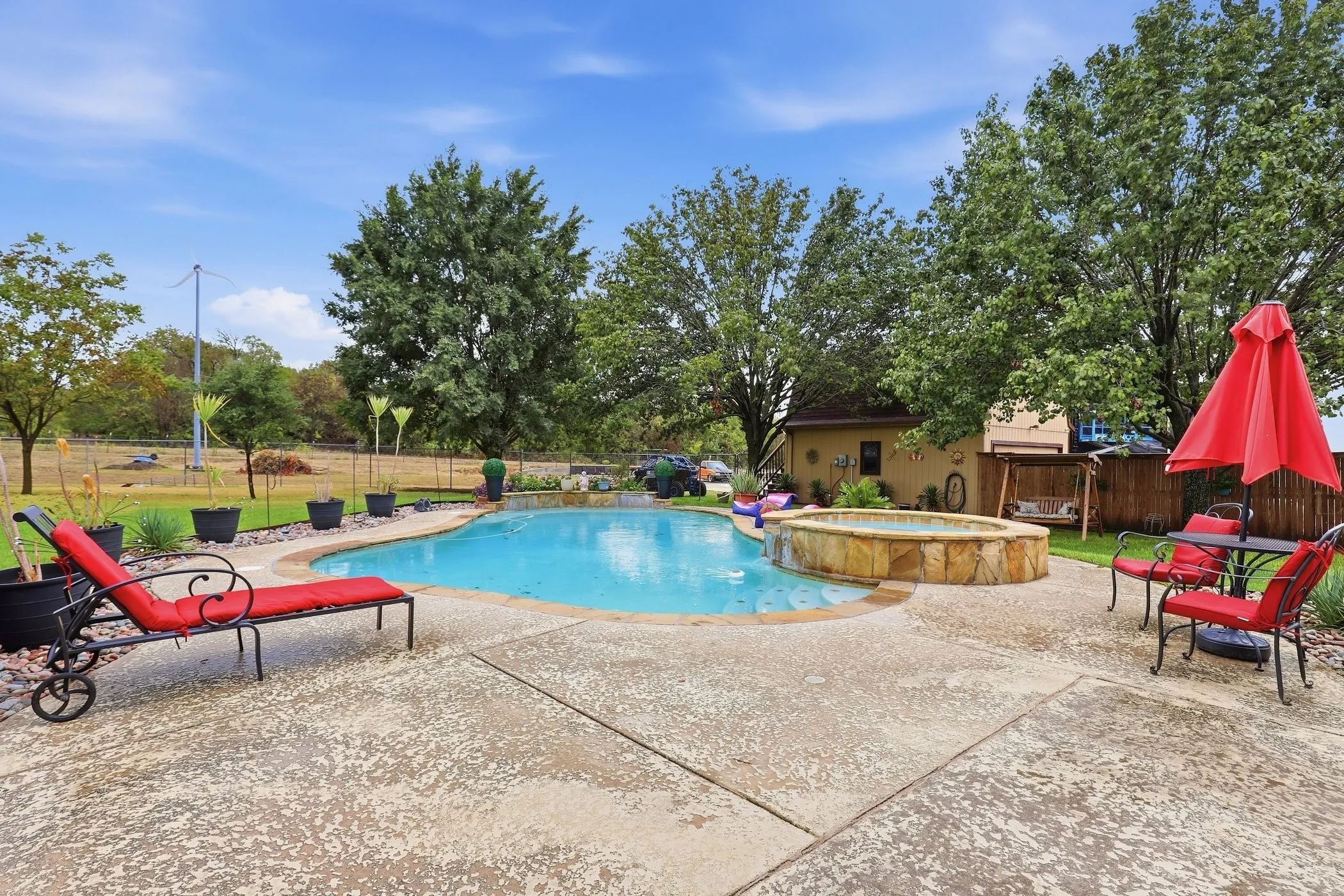 In-ground swimming pool with an integrated spa, surrounded by a concrete patio