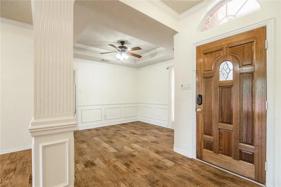 Wood-finish flooring throughout, decorative wainscoting, and a coffered ceiling with a ceiling fan