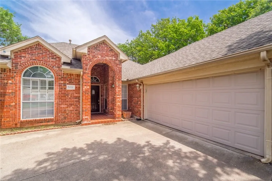 Brick exterior with an arched entryway, arched window, and a two-car garage