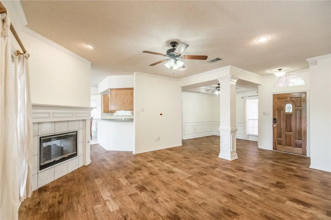 Wood-finish flooring throughout, tile-surround fireplace with mantel, decorative wood front door with arched transom, and recessed ceiling lighting