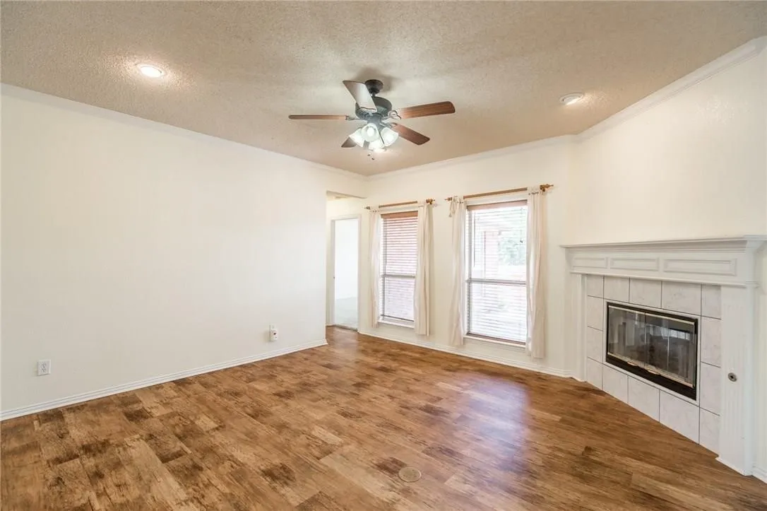 Wood-finish flooring, recessed lighting, ceiling fan, white trim, and a tiled fireplace