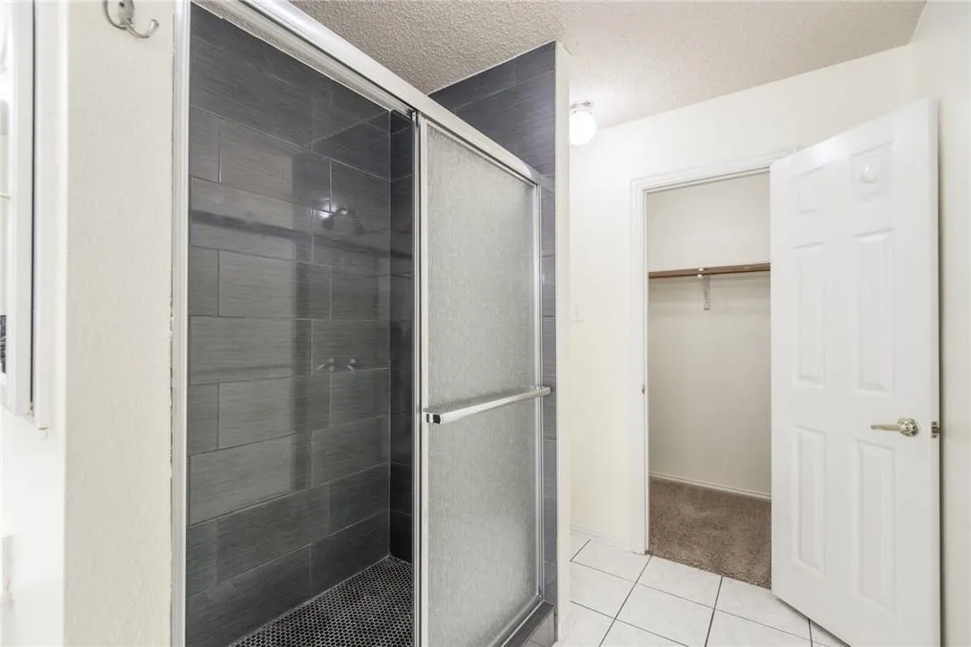 Enclosed shower with dark tile surround and sliding glass door