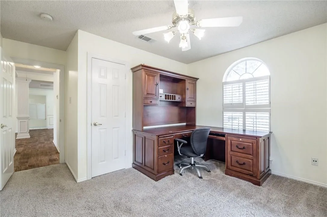 Arched window with plantation shutters, ceiling fan with integrated lighting, and neutral wall tones