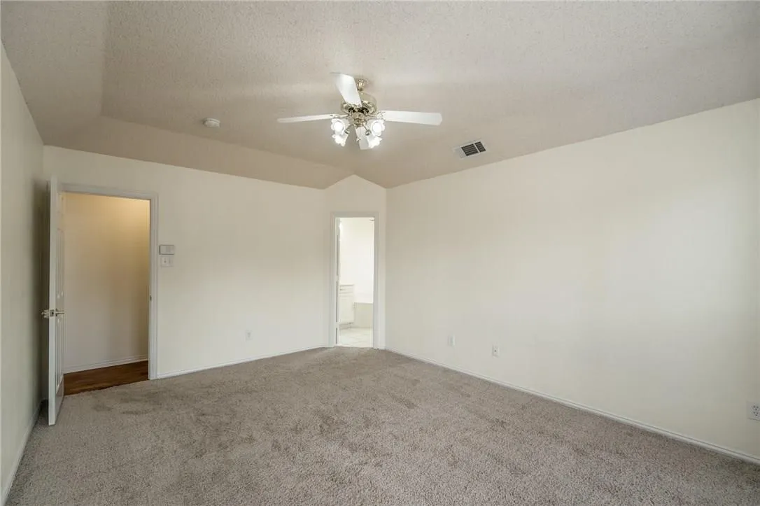 Vaulted ceiling with ceiling fan and light fixture, carpeted flooring, and neutral wall tones