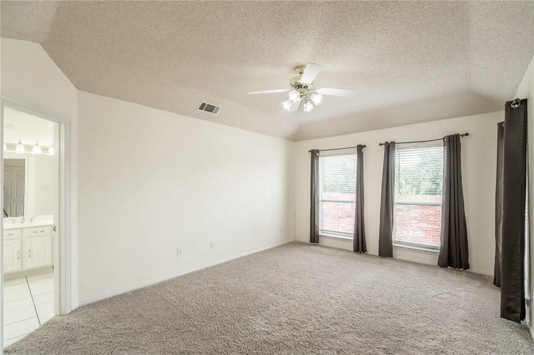 Carpeted room with a ceiling fan and three windows