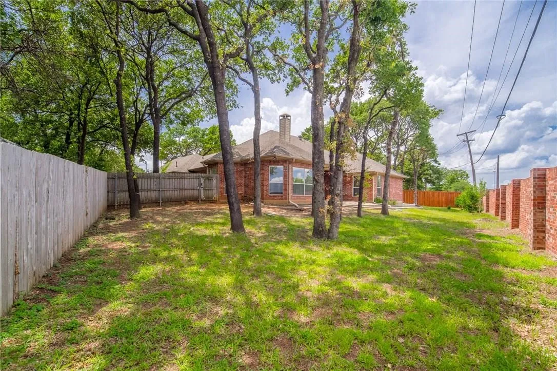 Expansive backyard featuring a manicured lawn, mature trees, and a wooden privacy fence