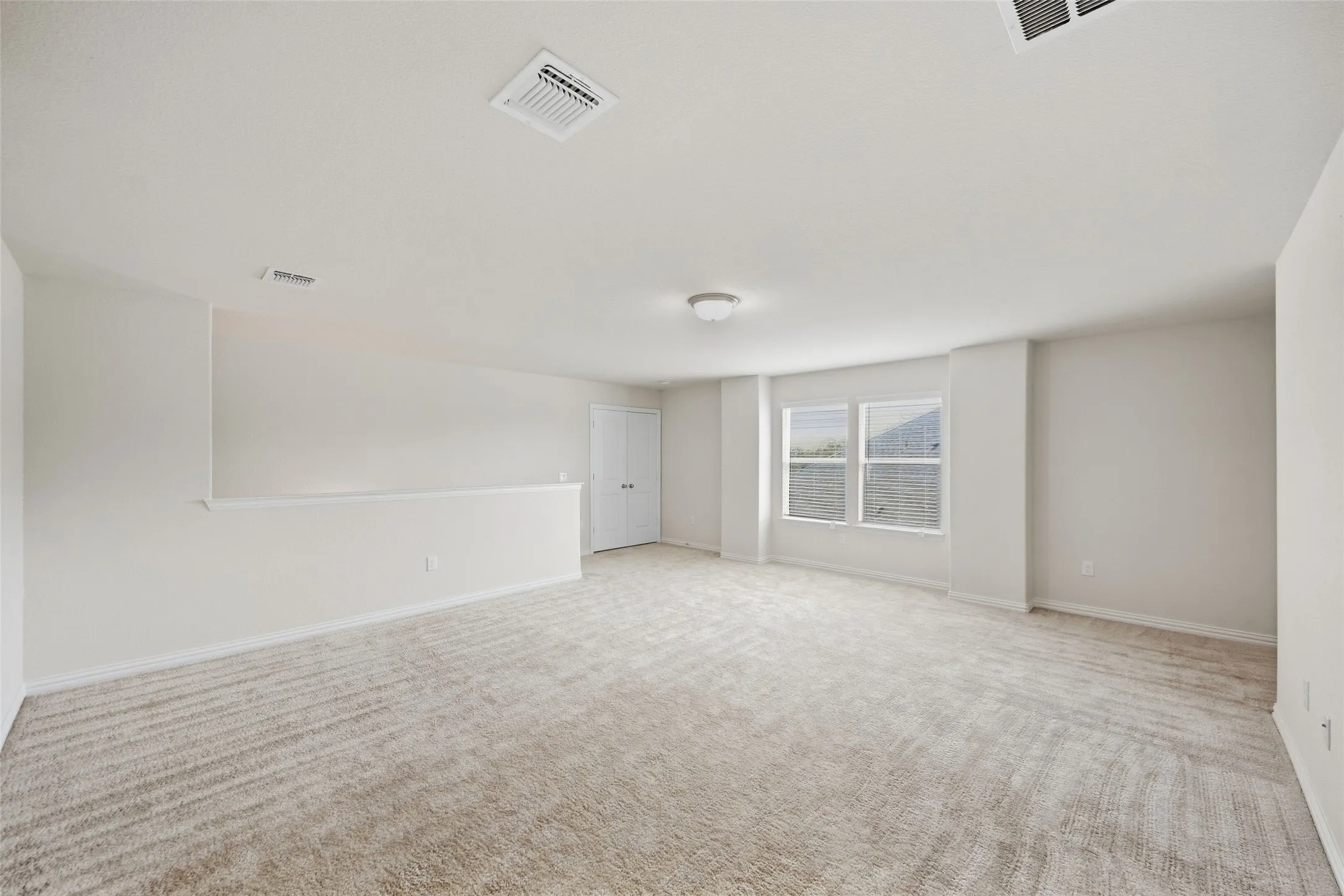 Expansive carpeted area with neutral wall finishes and natural light from multiple windows