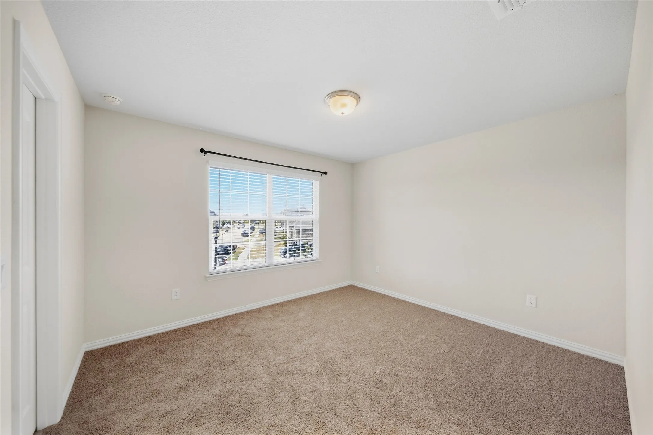 Neutral-toned walls, carpeted flooring, and a flush mount lighting fixture
