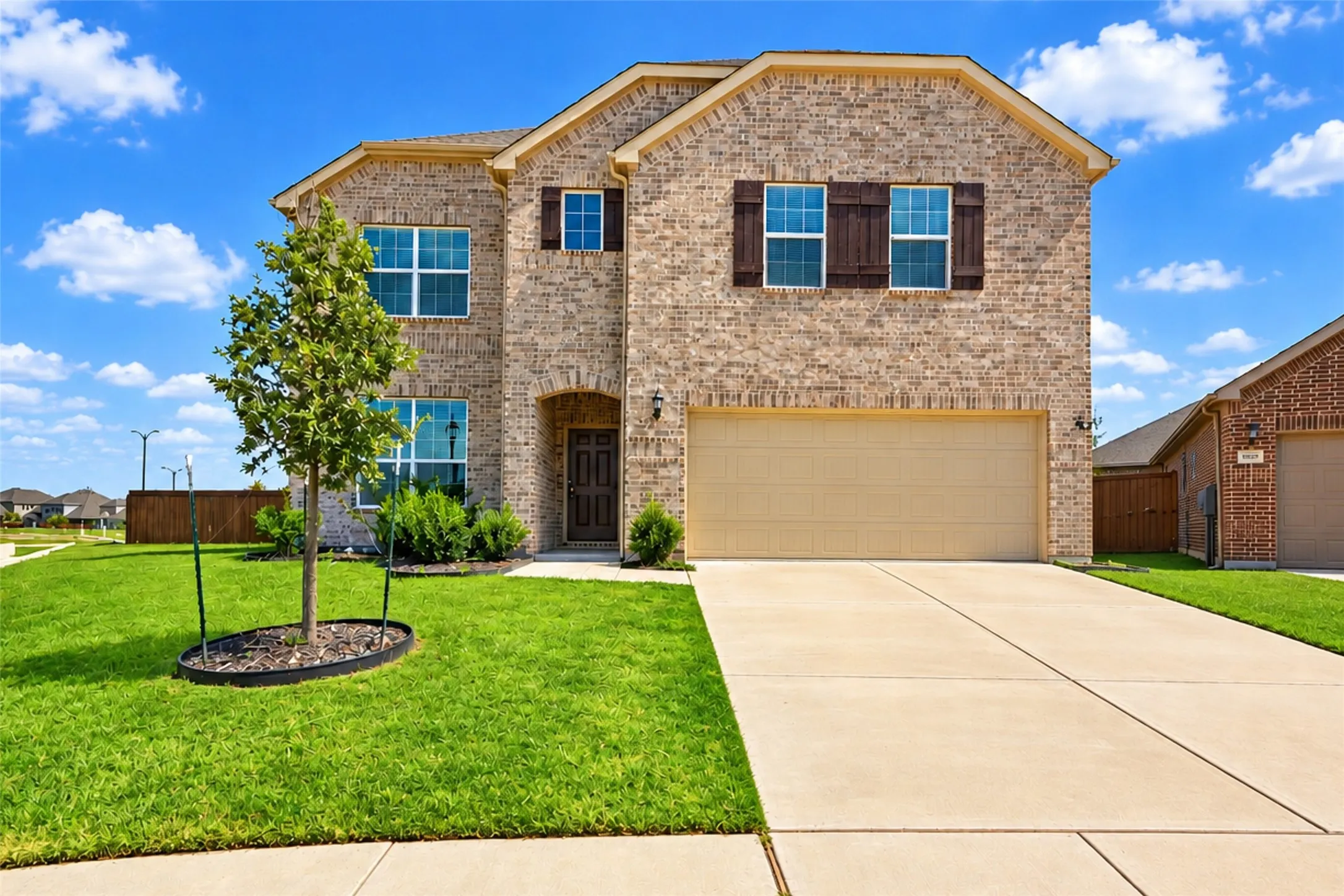 Brick exterior with wood shutters, concrete driveway, and attached garage
