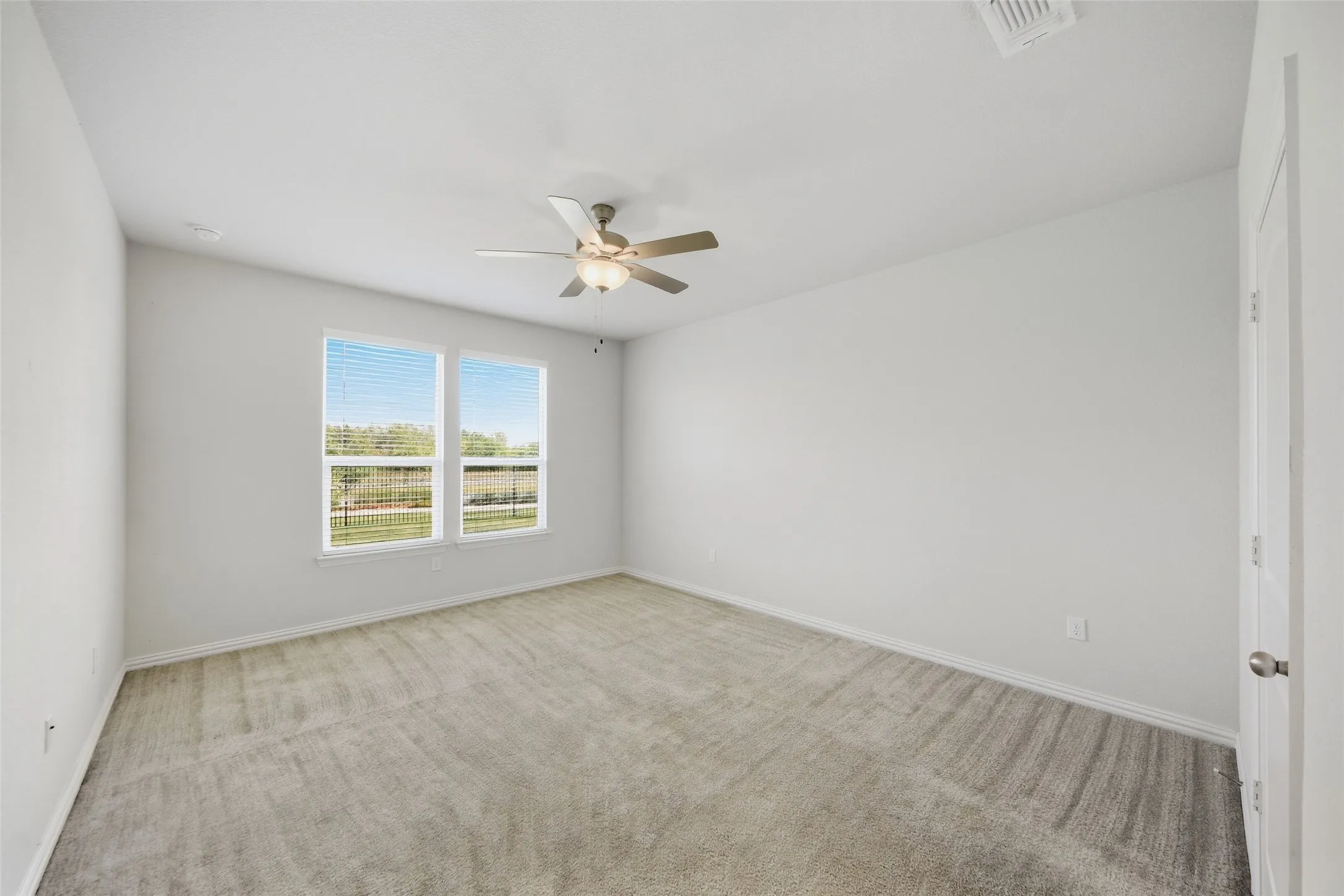 Recessed lighting, ceiling fan with light fixture, two windows with blinds, and light gray carpeting
