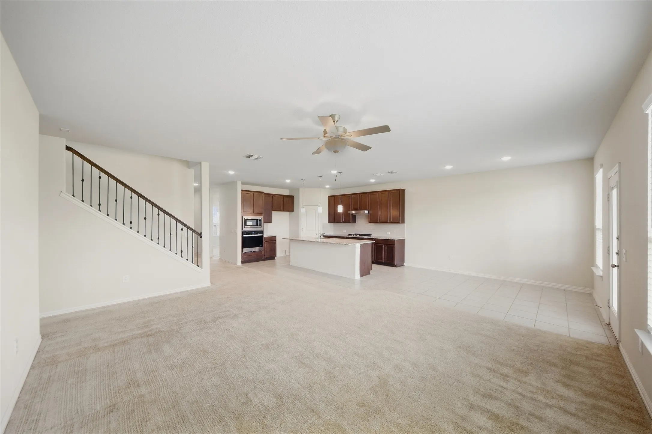 Open-concept living area with carpet and tile flooring