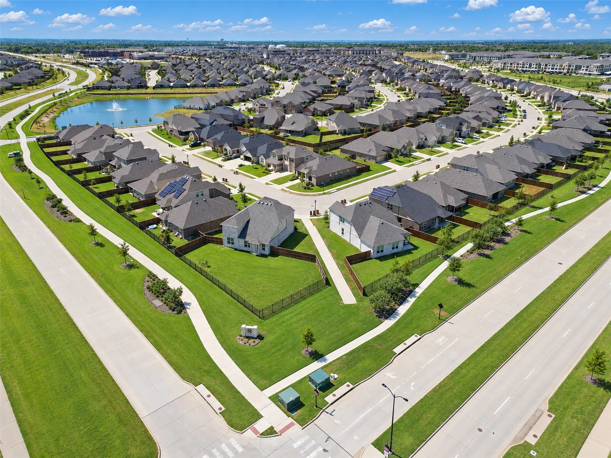 Residential community with a curving street layout, a central pond, and multiple properties featuring green lawns