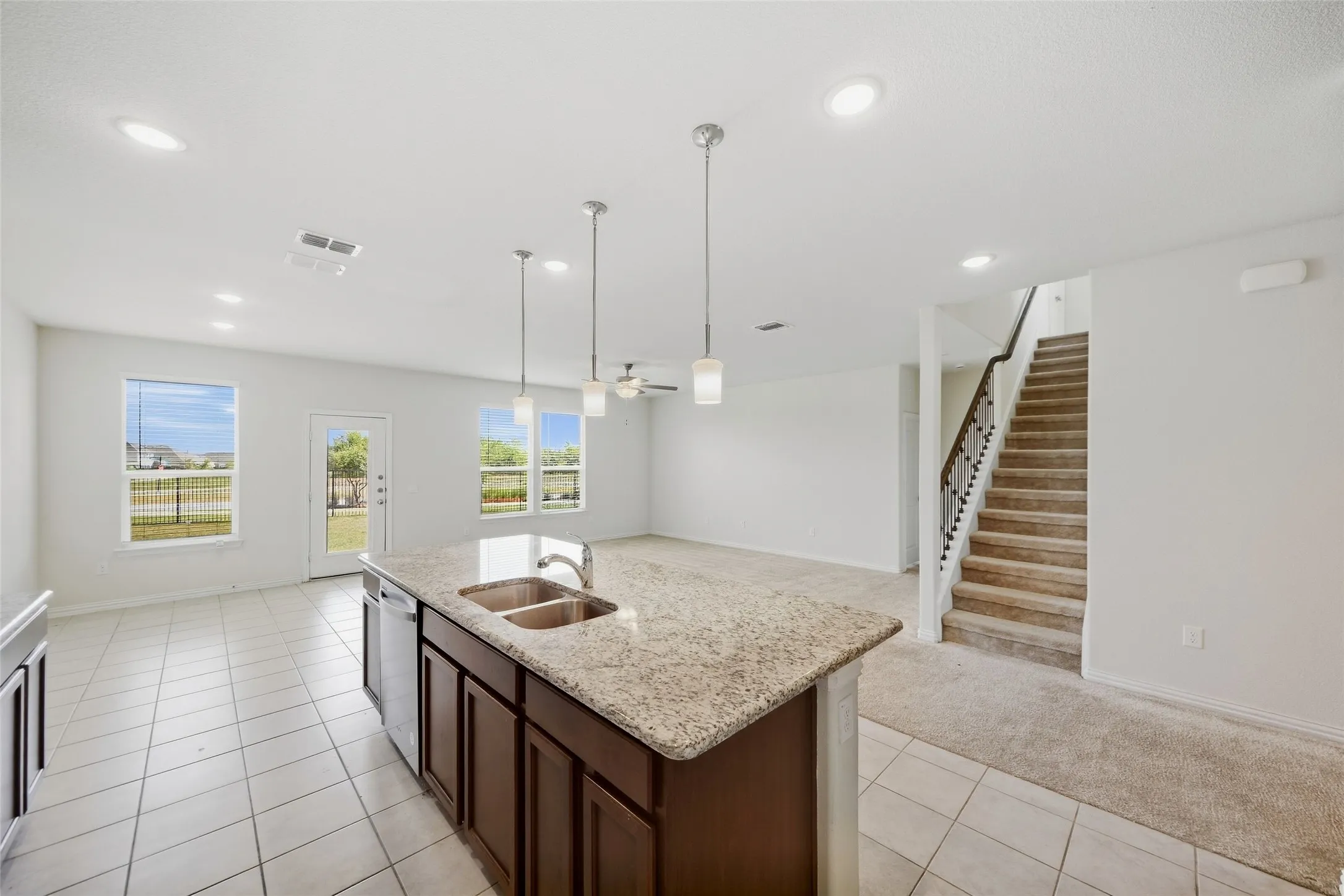 Kitchen island with integrated double sink, granite-style countertop, and pendant lighting