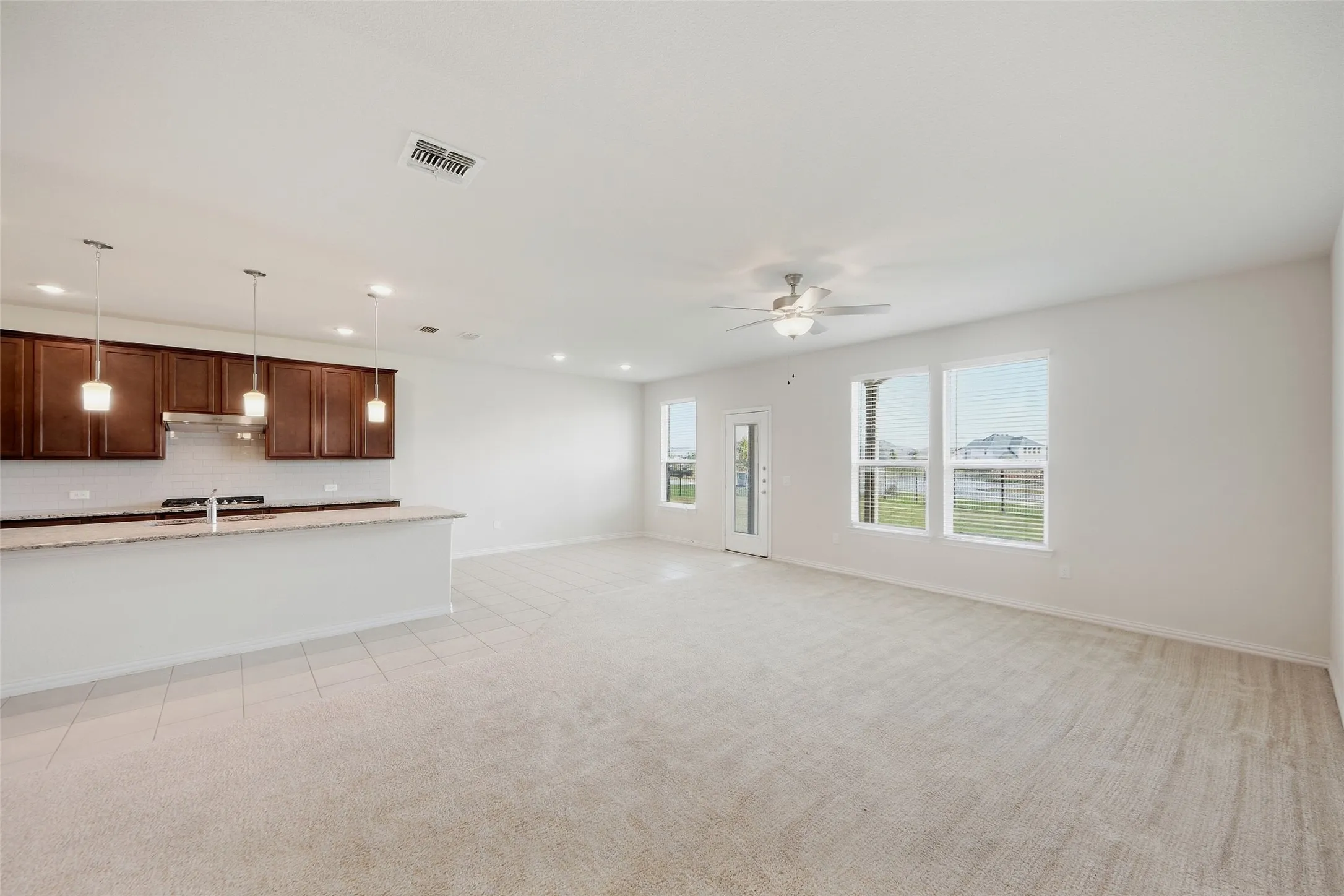 Open-concept living area with light-toned carpet and recessed lighting