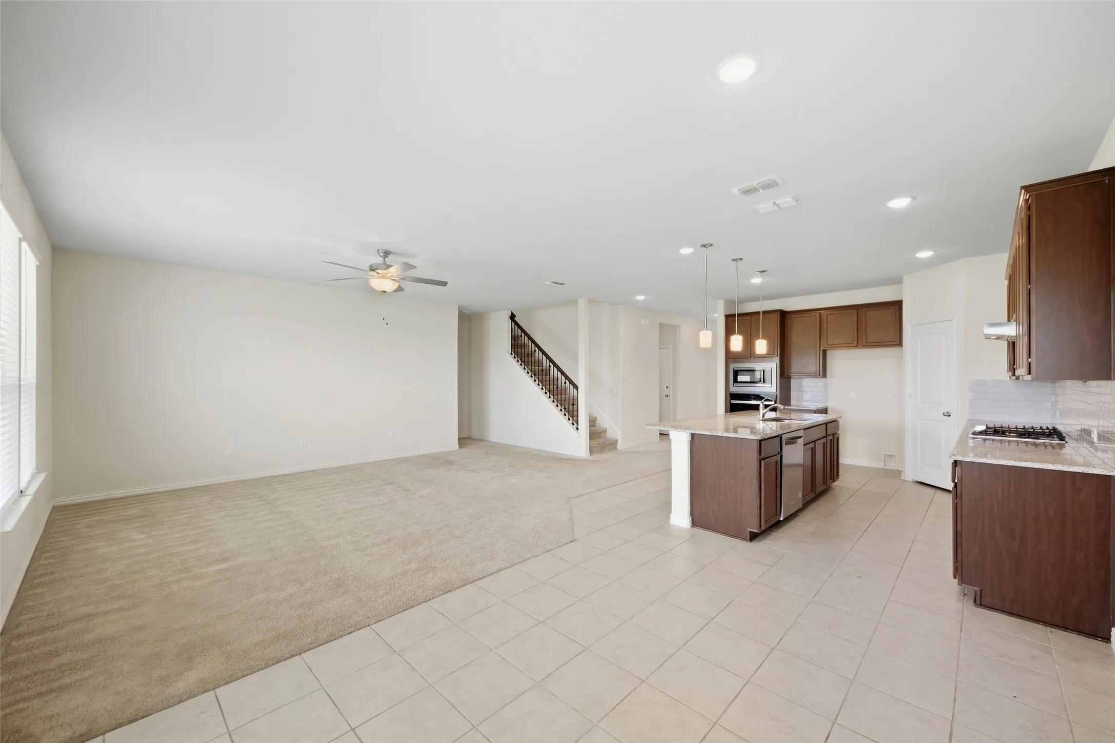Open-concept living area with carpet and tile flooring