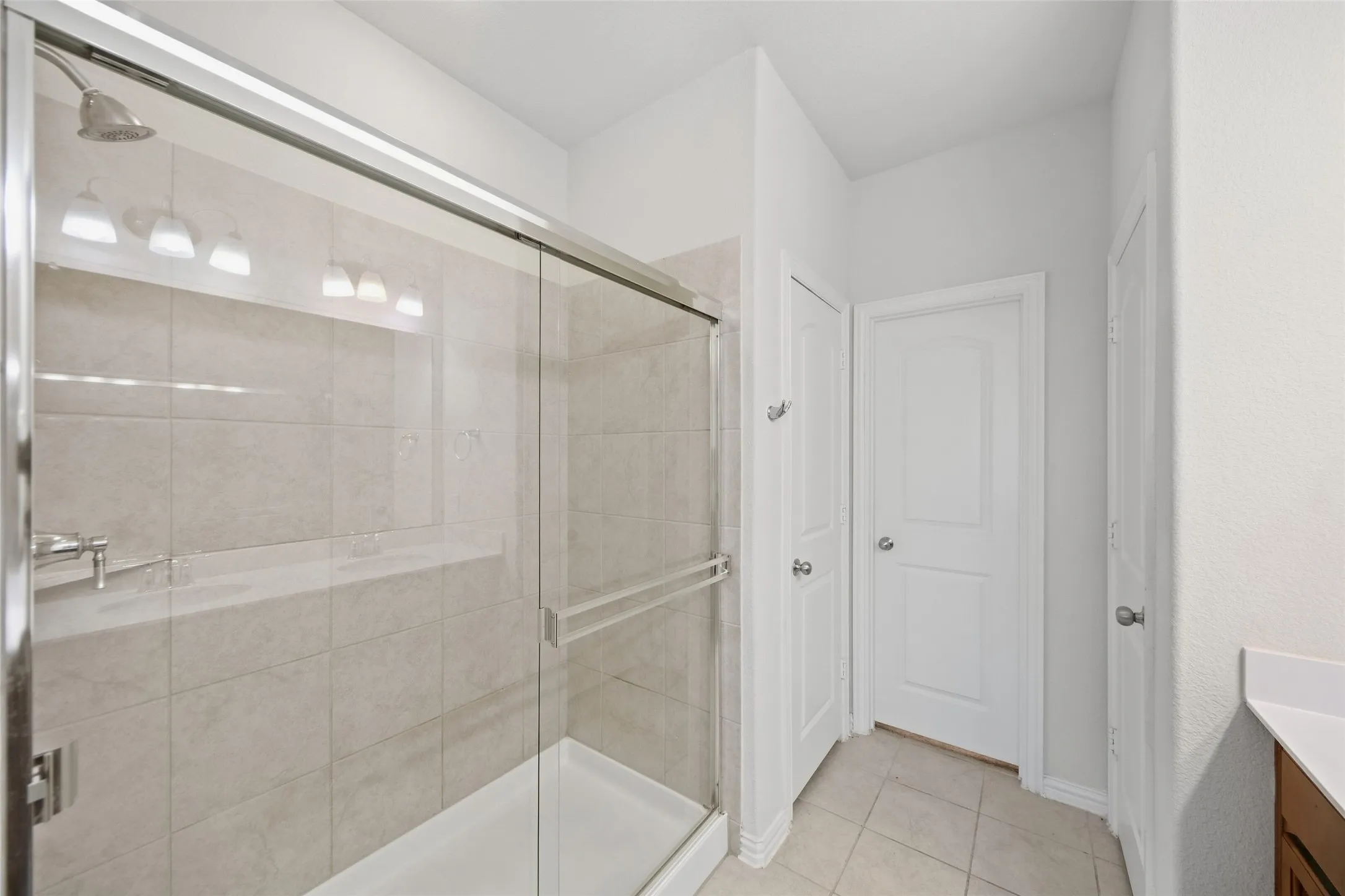 Glass-enclosed shower with a tiled surround, built-in ledge, and brushed nickel showerhead
