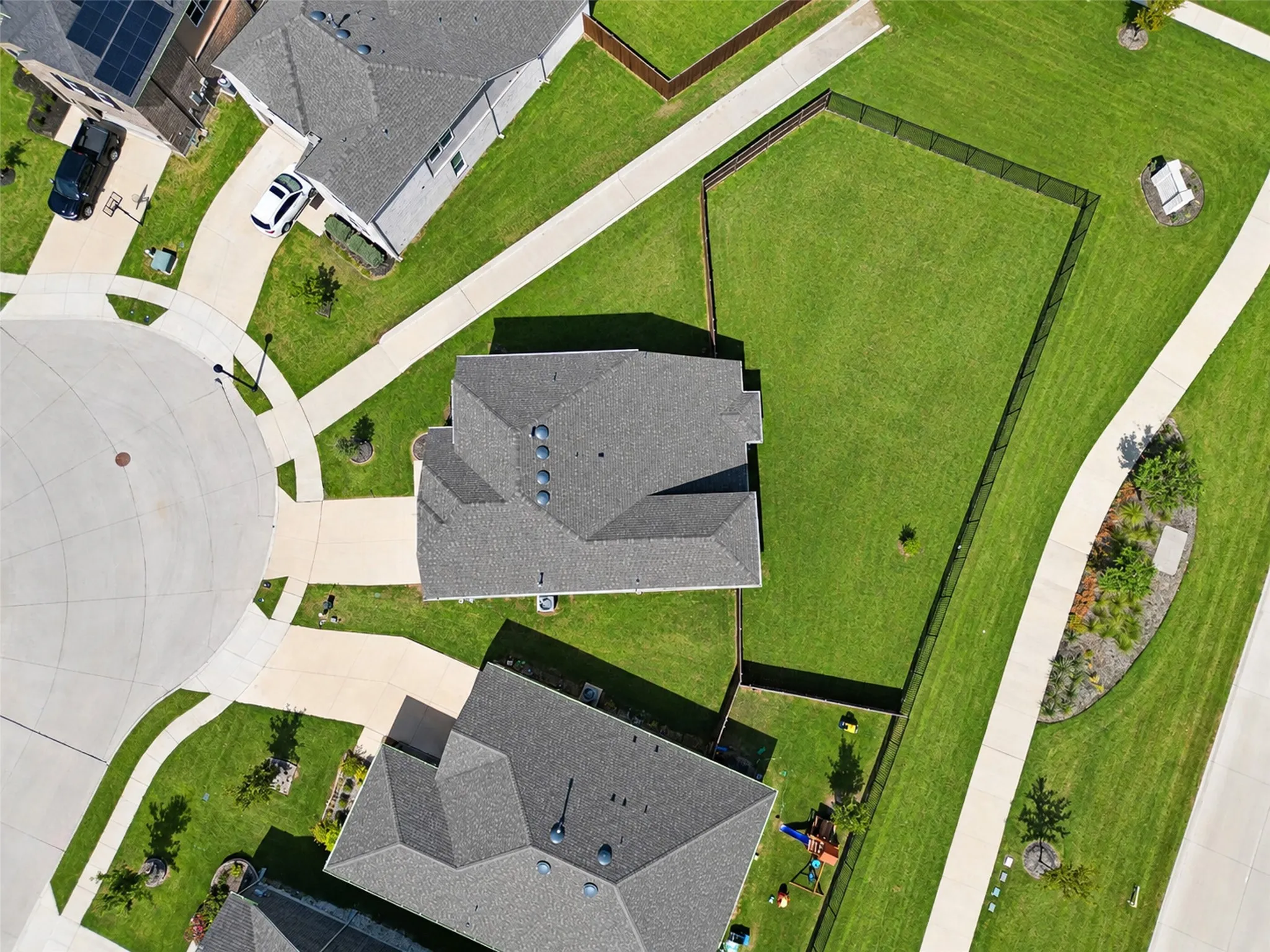 Expansive grassy yard with perimeter fencing, concrete pathways, and surrounding residential structures