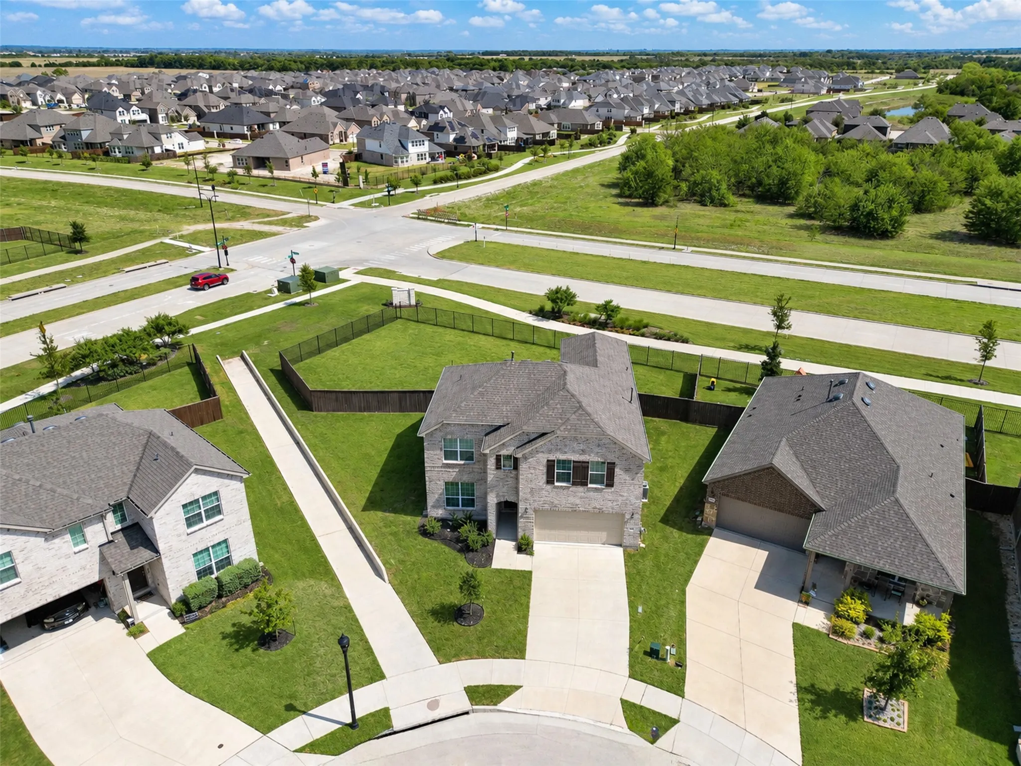 Two-story brick exterior, attached two-car garage, concrete driveway, front yard landscaping, mature trees