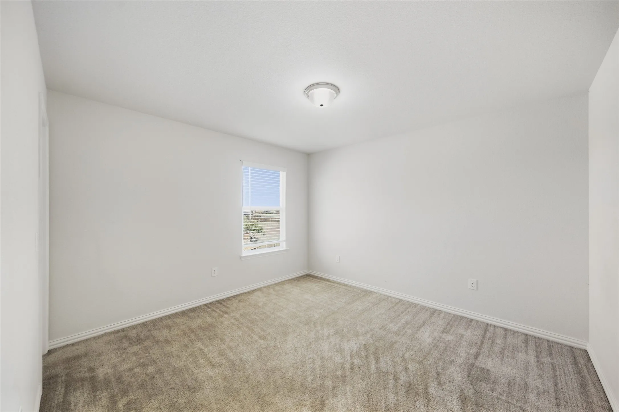 Carpeted flooring, white walls, window with blinds, overhead lighting fixture