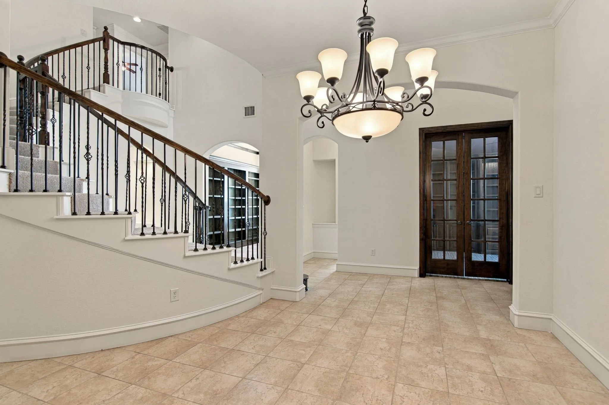 Curved staircase with wrought iron balusters and wood handrail