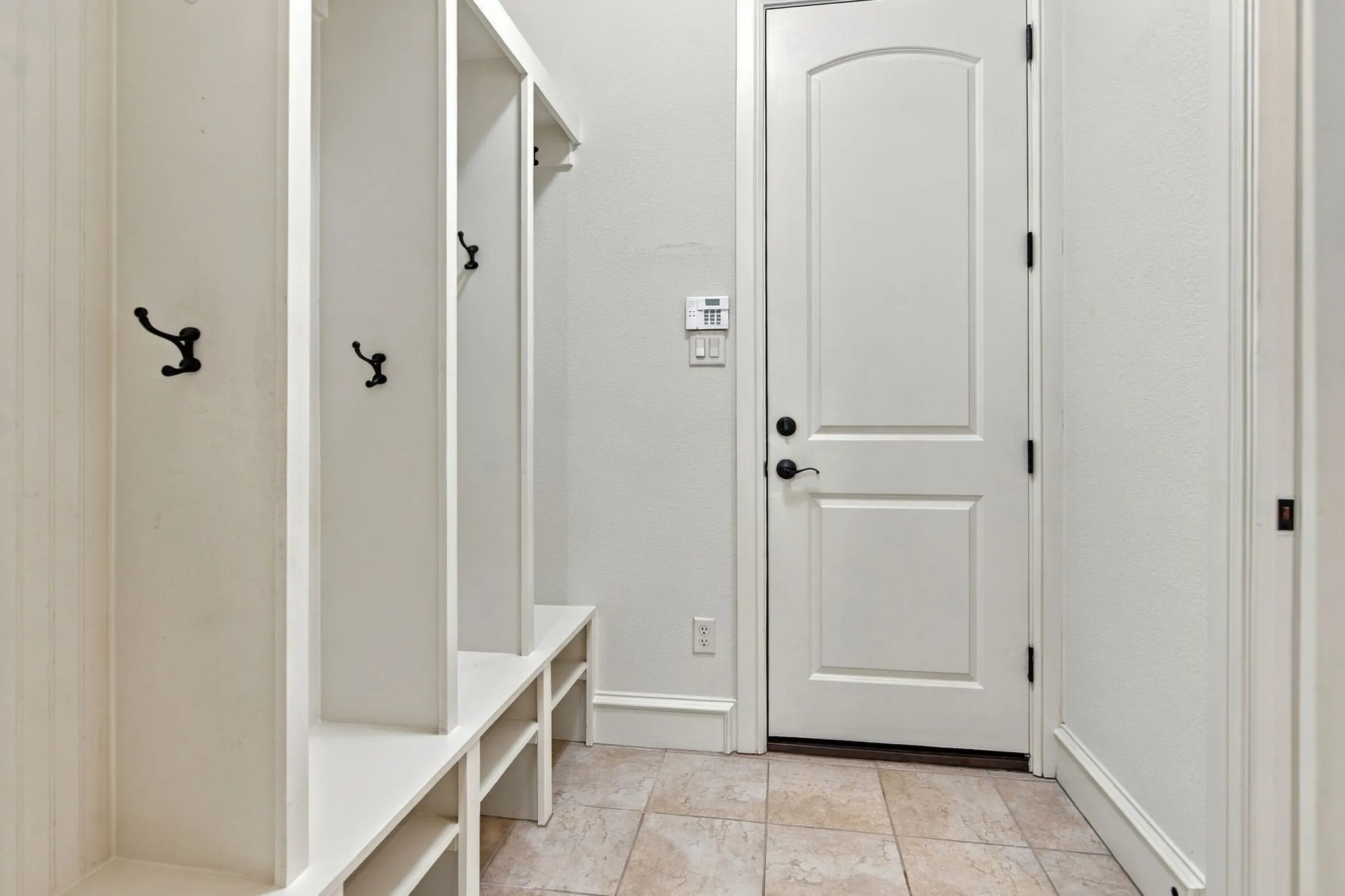 Built-in white cubbies with black hooks, bench seating, and lower storage