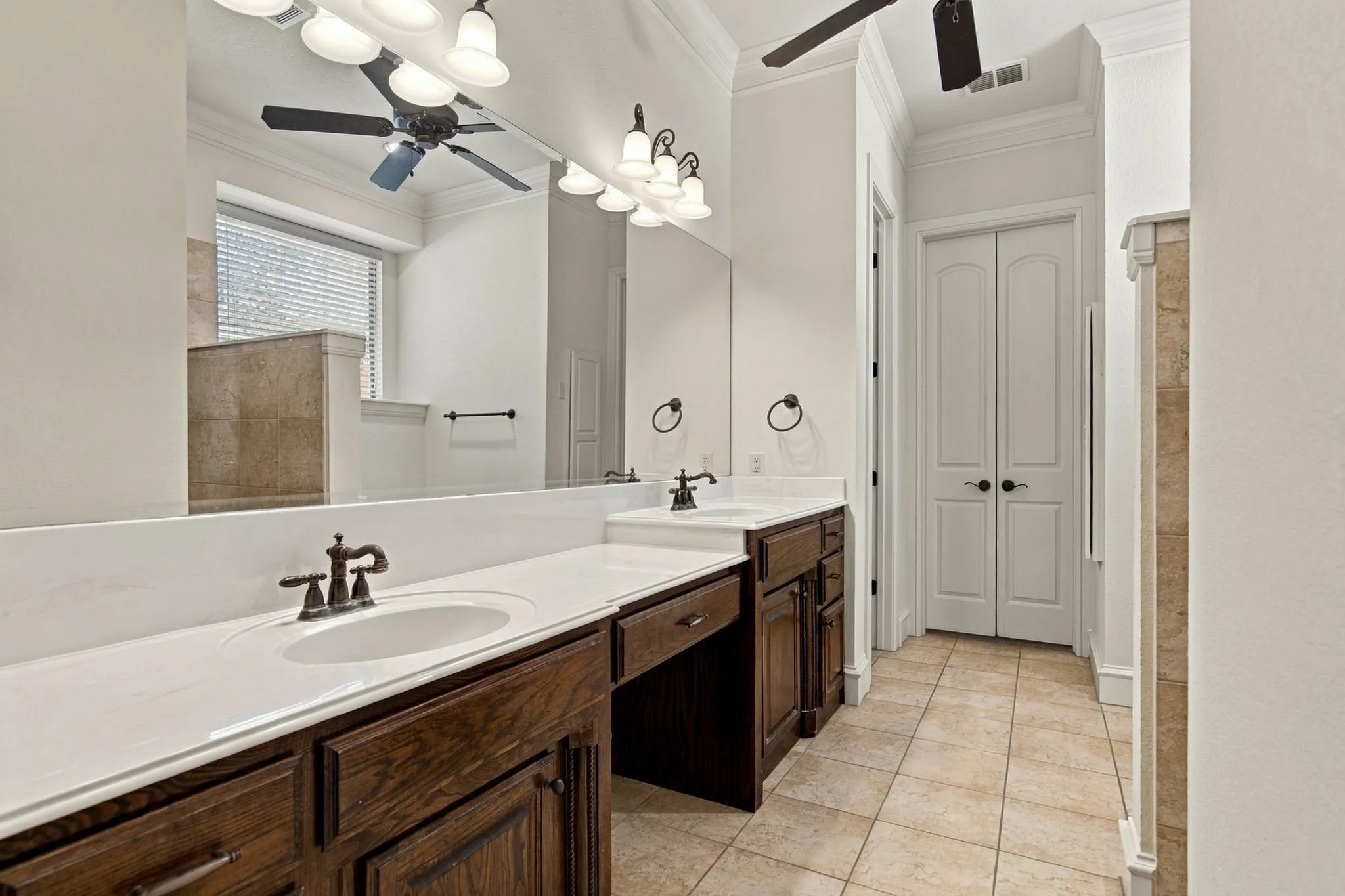 Double vanity with white countertops, dark wood cabinetry, and oil-rubbed bronze fixtures