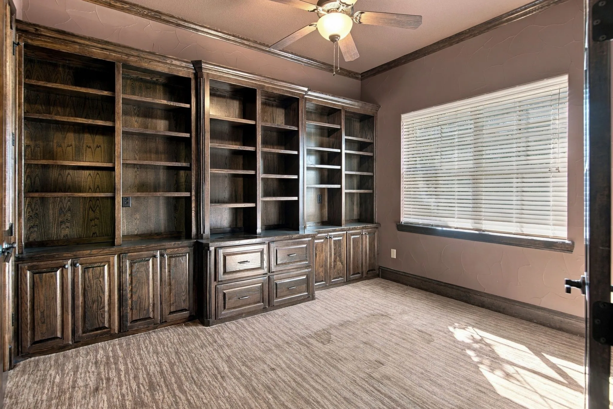 Built-in wood cabinetry, integrated shelving, and window with horizontal blinds