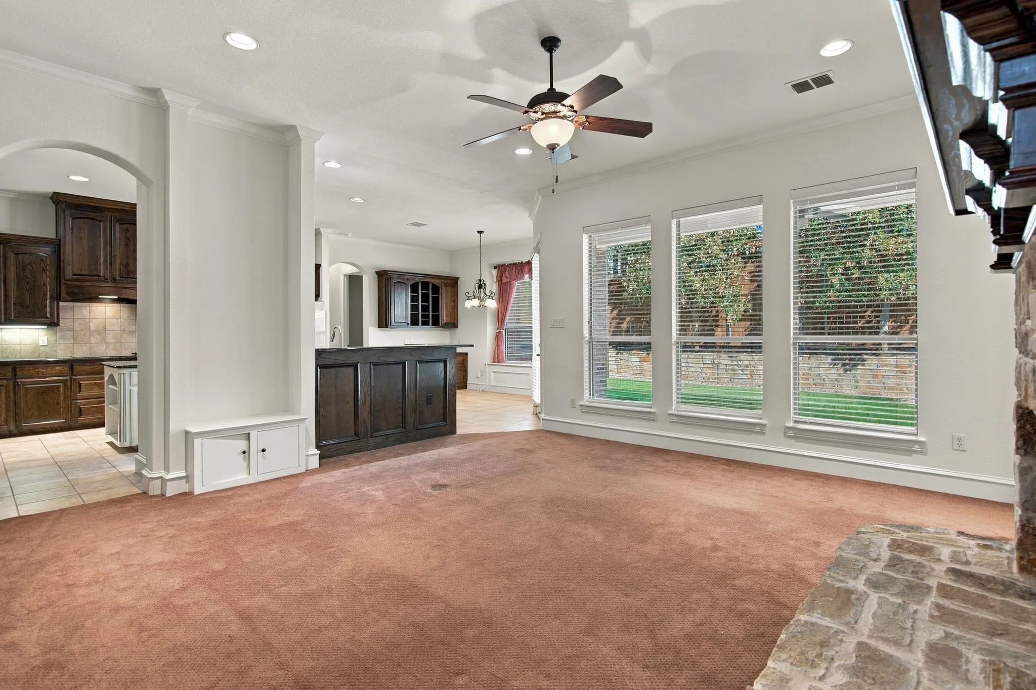 Recessed lighting, ceiling fan with integrated lighting, built-in cabinetry, stone-clad fireplace, and multiple windows